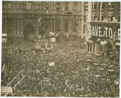 Crowd gathered for a historic protest or rally on a city street with flags and banners, early 20th-century, high attendance, American flags, vintage atmosphere, social activism, public demonstration.