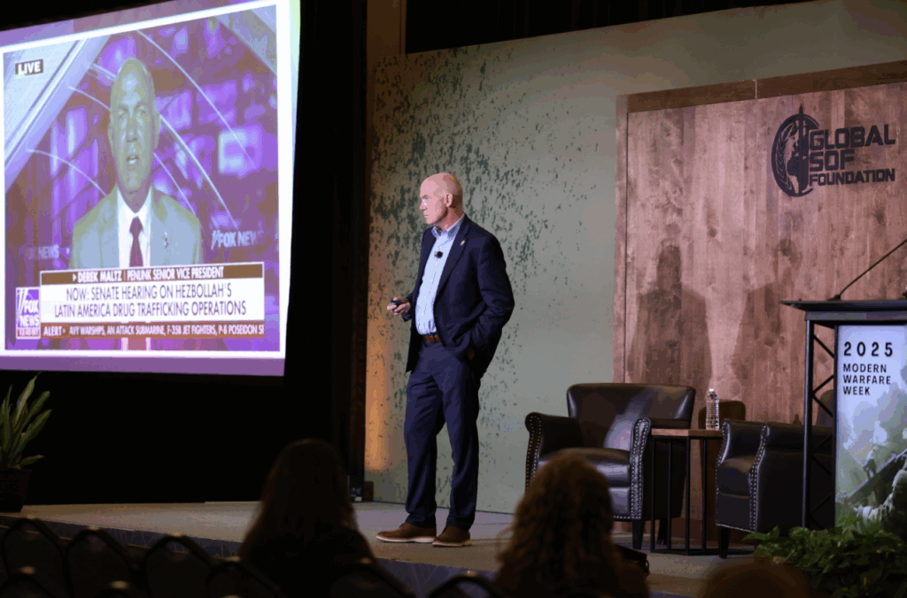 Derek Maltz speaking at Modern Warfare Week event, presenting on global security issues in front of an audience.